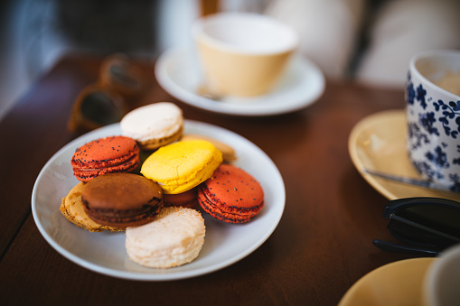 Colorful traditional gourmet French macarons served as desert with coffee and tea on wooden table