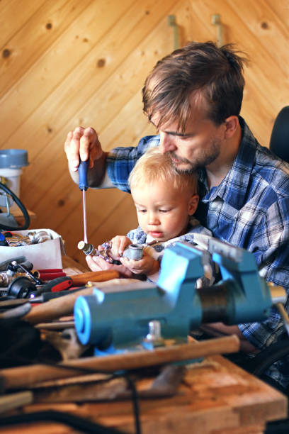 istock Father and son in workshop repairing some stuff. Cute boy exploring tools. Fatherhood concept. 987763718