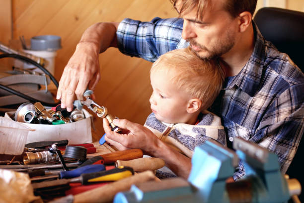 istock Father and son in workshop repairing some stuff. Cute boy exploring tools. Fatherhood and  transfer of experience concept. 987764014
