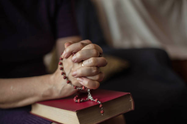 Woman sitting,holding rosary over bible,close up.