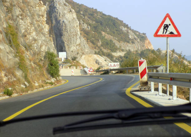 istock Road construction after double bend on the mountain road, with warning signs 987781332