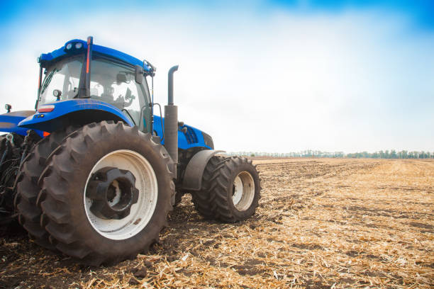 istock Blue tractor on the background of an empty field 987789478