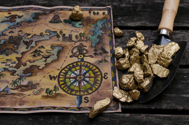 Treasure chest map. Treasure map and shovel full of gold nuggets ore on wooden table. Treasure hunter or gold miner concept. gold mining panning stock pictures, royalty-free photos & images