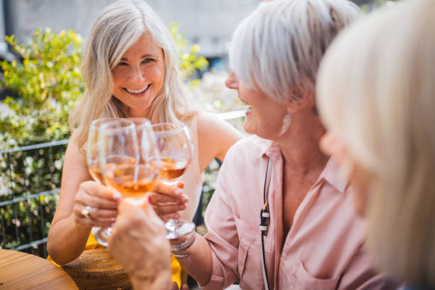Senior women on holidays toasting with wine during wine tasting Fashionable mature women having fun toasting and drinking wine at luxurious restaurant in France wine tasting stock pictures, royalty-free photos & images