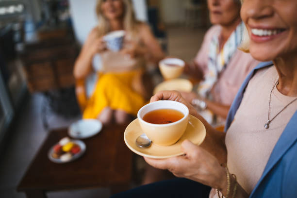 Mature female friends enjoying a cup of tea at cafe stock photo