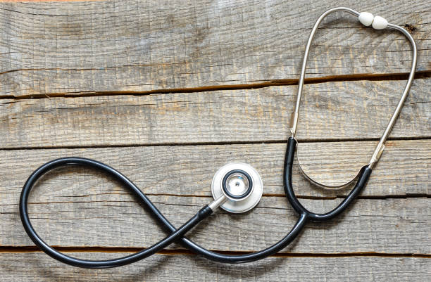 istock Black stethoscope. Black stethoscope on a wooden background. 987828894