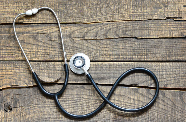 istock Black stethoscope. Black stethoscope on a wooden background. 987831444