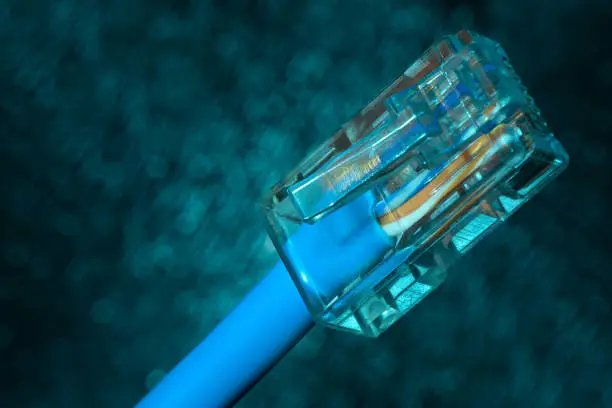 Photo of The concept of Internet technology. Twisted pair (patch cord) network Internet cable on blue blurred background closeup