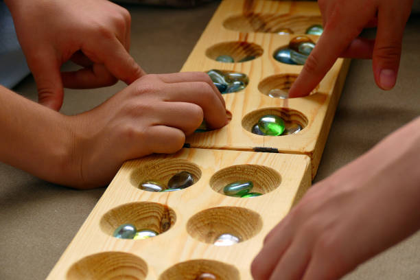 dos personas jugando un juego de mancala, - traditional games fotografías e imágenes de stock