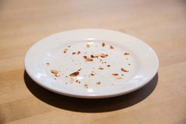 Empty white plate with bread crumbs on wood table