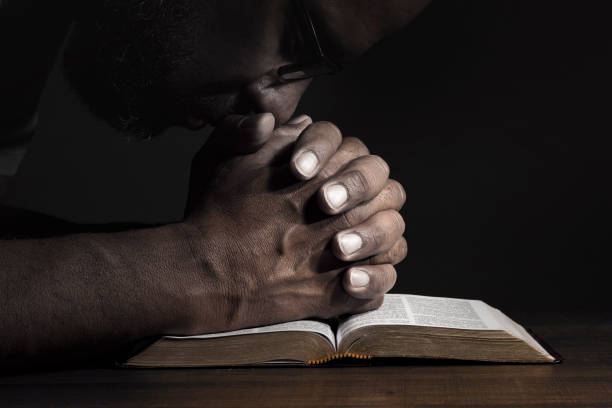istock Man praying to God on a Bible 987914432