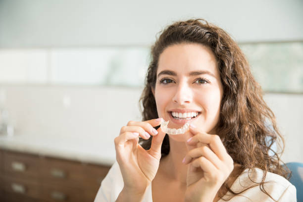 beautiful patient holding orthodontic retainers in dental clinic - adult beautiful caucasian equipment imagens e fotografias de stock