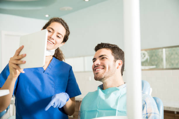 lächelnd, zahnarzt und patient blick auf digital-tablette in klinik - dentist dentist office patient discussion stock-fotos und bilder