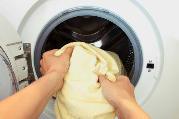 istock Womans hands pull the laundry out of or load the washing machine 987929514