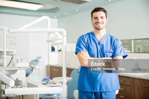 Portrait Of Confident Dentist Standing With Arms Crossed In Clinic Stock Photo - Download Image Now