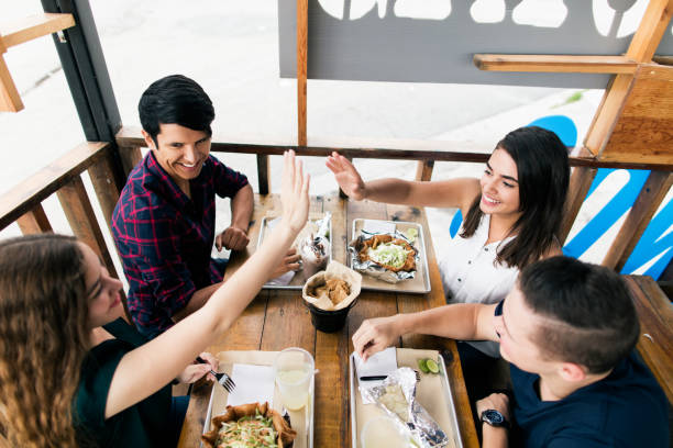 istock Four friends enjoying meal at restaurant and smiling 987935862