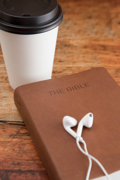 Physical Bible and a Smart Phone with Earphones on a Wood Table