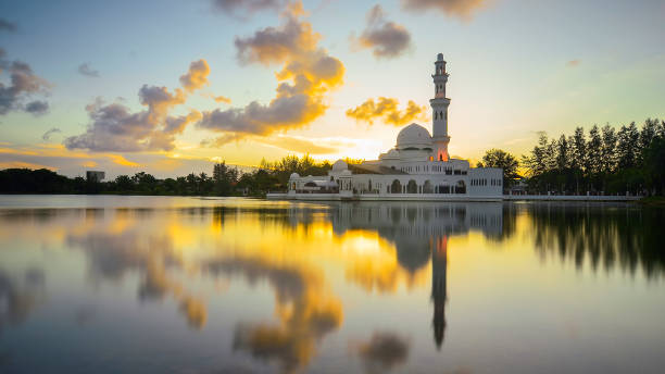 istock Mirror reflection of beautiful white floating mosque in a lake during sunset. 987970900
