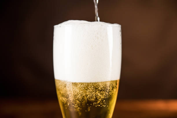 istock Cold beer being poured into the glass with frothy foam 987982960