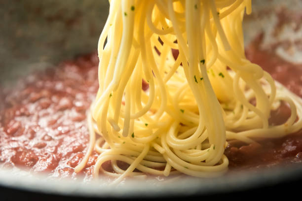 istock spaghetti being put into hot bolognese sauce in the pan 987983694