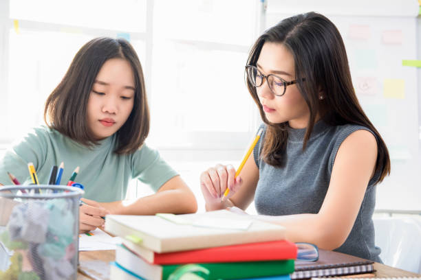 Female Asian Chinese college students doing assignment in class room Group of female Asian Chinese college students doing assignment at the table in classroom dissertation photos stock pictures, royalty-free photos & images