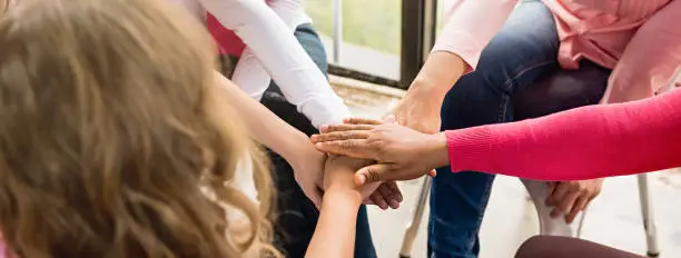 Photo of Women put their hands together in breast cancer awareness campaign meeting