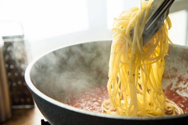 istock spaghetti being put into hot bolognese sauce in the pan 987983780