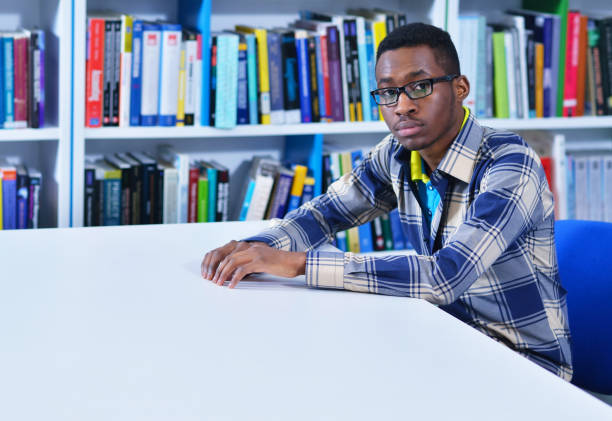 istock Male african american college student reading in library 987991578