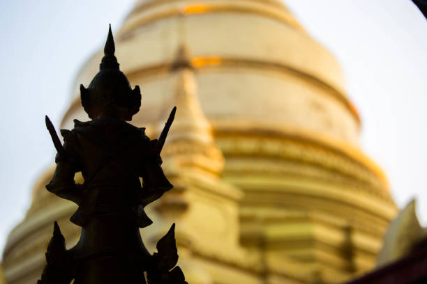 The silohuette of a statue against the gold background of the Su Taung Pyae Pagoda (Sataungpyei Temple) in Mandalay.