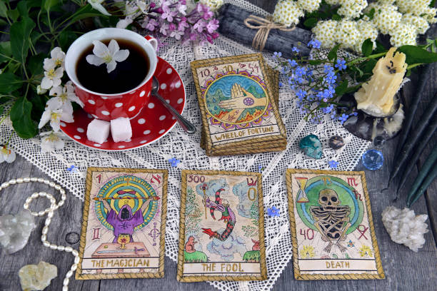 Tarot cards with cup of tea, flowers and black candles on planks stock photo