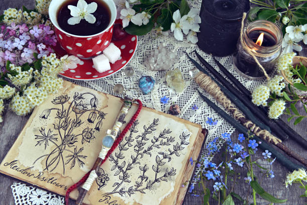 istock Witch book with magic and healing herbs, black candles and cup of tea 988017140