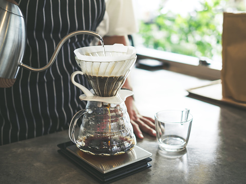 Barista Brewing Drip Coffee, Hand Pouring Hot Water from The Kettle over The Coffee Powder.