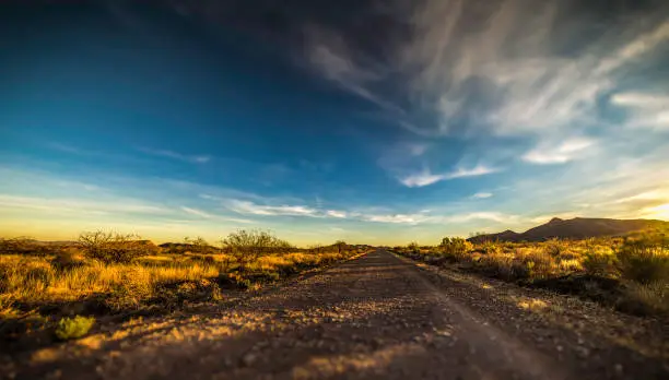 Arizona dirt road at sunset, shot with a very low angle of view, golden light and high clouds make an amazing picture