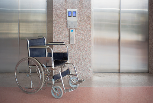 Wheelchair and elevator for disabled, wheelchair waiting in front of elevator in hospital