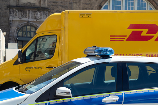 Hamburg, Germany - June 26. 2018: A DHL delivery van parked behind a police car in Hamburg, Germany