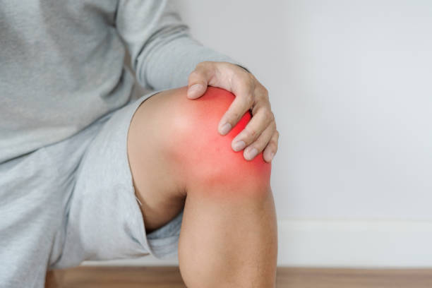 赤の膝に触れる男ハイライト膝や関節の痛みの概念 - pain joint human hand arthritis ストックフォトと画像