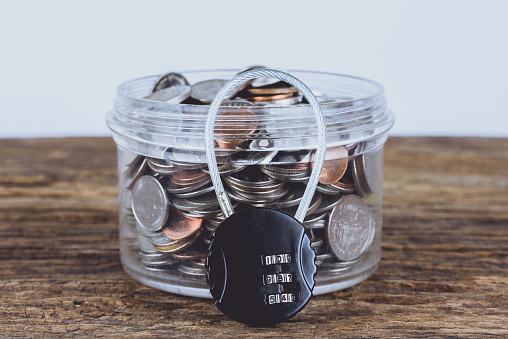 Black security lock with pass-code or password and full coins with jar. Save Money Concept and used for financial protection inferences or other investment messages
