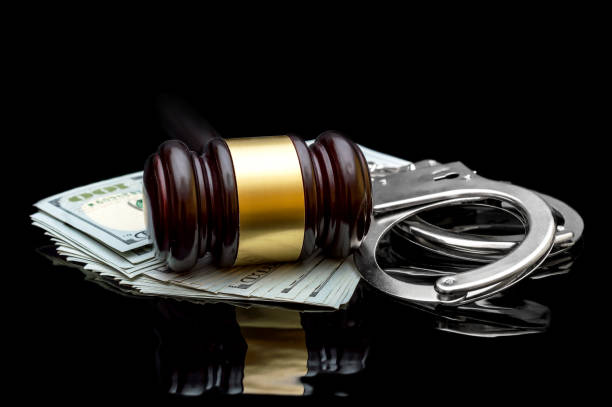 istock Gavel with handcuffs and money on black reflective background. 988152856