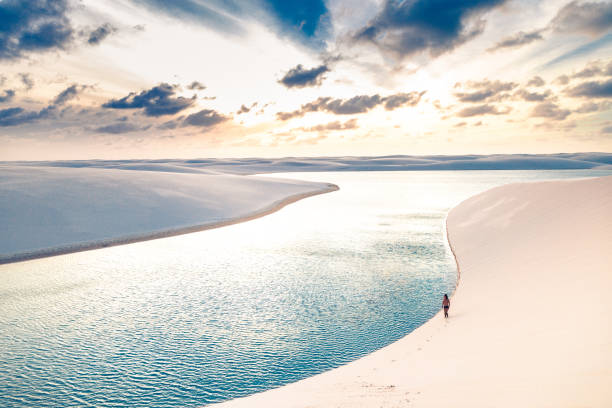 Young man walking on the sand dunes of Lençois Maranhenses Young man walking on the sand dunes of Lençois Maranhenses brazil desert maranhao state national park stock pictures, royalty-free photos & images