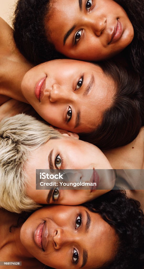 Beautiful young women lying on top of each other, looking at camera Women Stock Photo