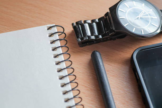 istock Wooden office desk table with notebook, smartphone, pen and watch. 988177284