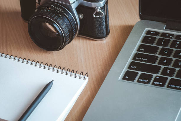 istock Wooden office desk table with notebook, pen, computer and retro camera. 988177424