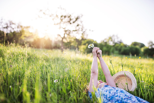 A small girl lying on the grass in spring nature, holding flowers. Copy space.