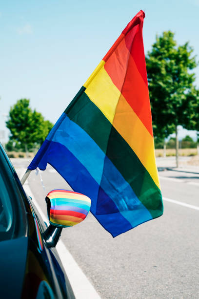 istock rainbow flag popping up from the window of a car 988191248