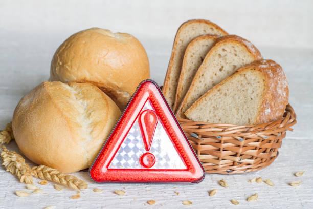 istock Gluten intolerance with bread wheat and warning sign on white planks 988201048