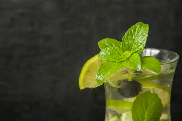 istock Summer refreshing drinks lemonade or cocktail Mojito with lime fresh mint blueberry ice. Dark wall 988213240