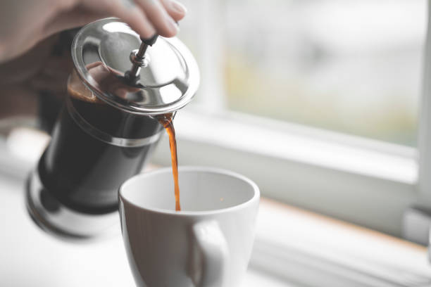 versando caffè dalla stampa francese sul davanzale della finestra - pouring coffee human hand cup foto e immagini stock