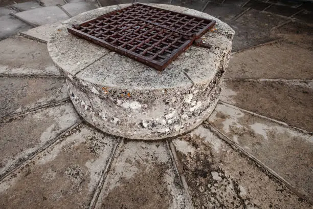 Stone well with rusted metal lattice mounted on the top of old castle tower