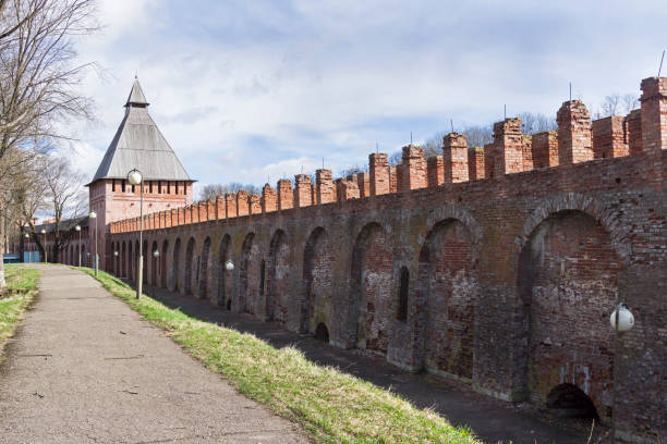 Long, enclosed brick corridor with evenly spaced openings in Nizhny Novgorod kremlin. Warm lighting and linear perspective enhance historical atmosphere. Wooden ceiling adds rustic charm