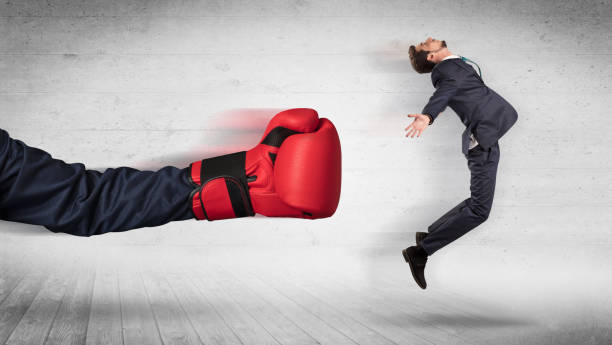 istock Arm with boxing gloves hits office worker concept 988235958
